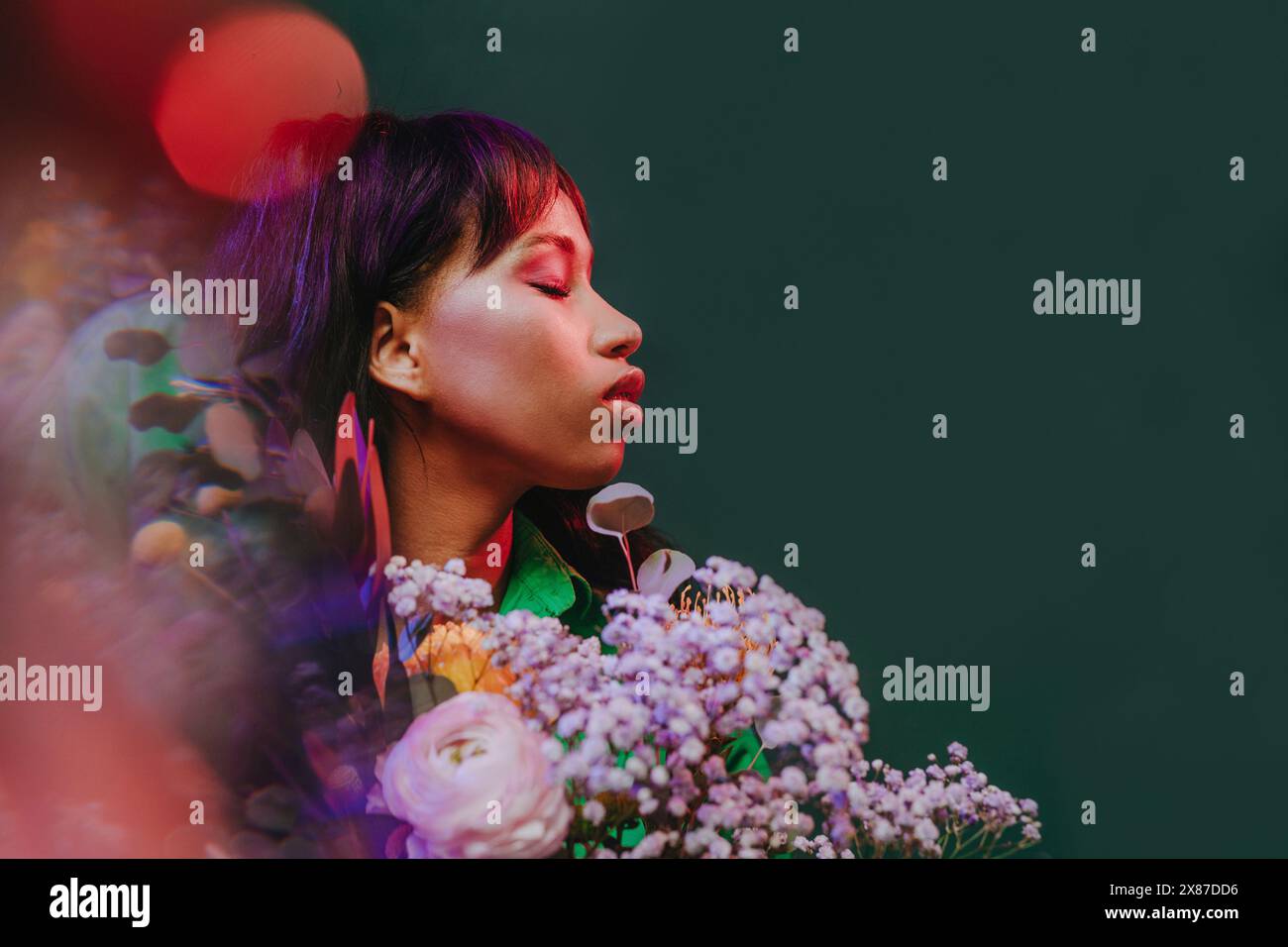 Woman with eyes closed amidst flowers and neon lights in front of green ...