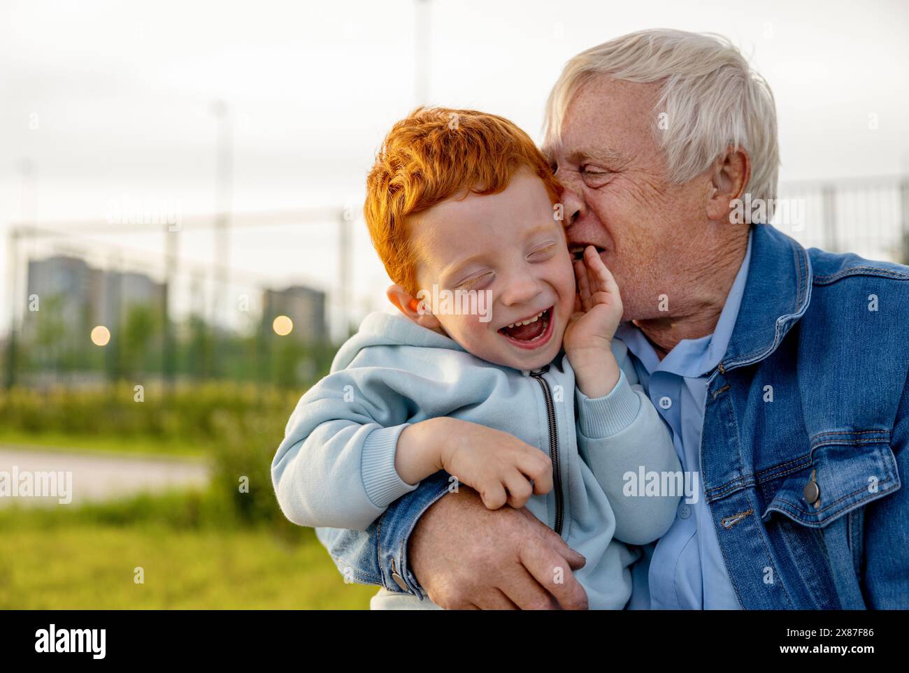 Senior man in denim jacket spending leisure time with grandson at park Stock Photo