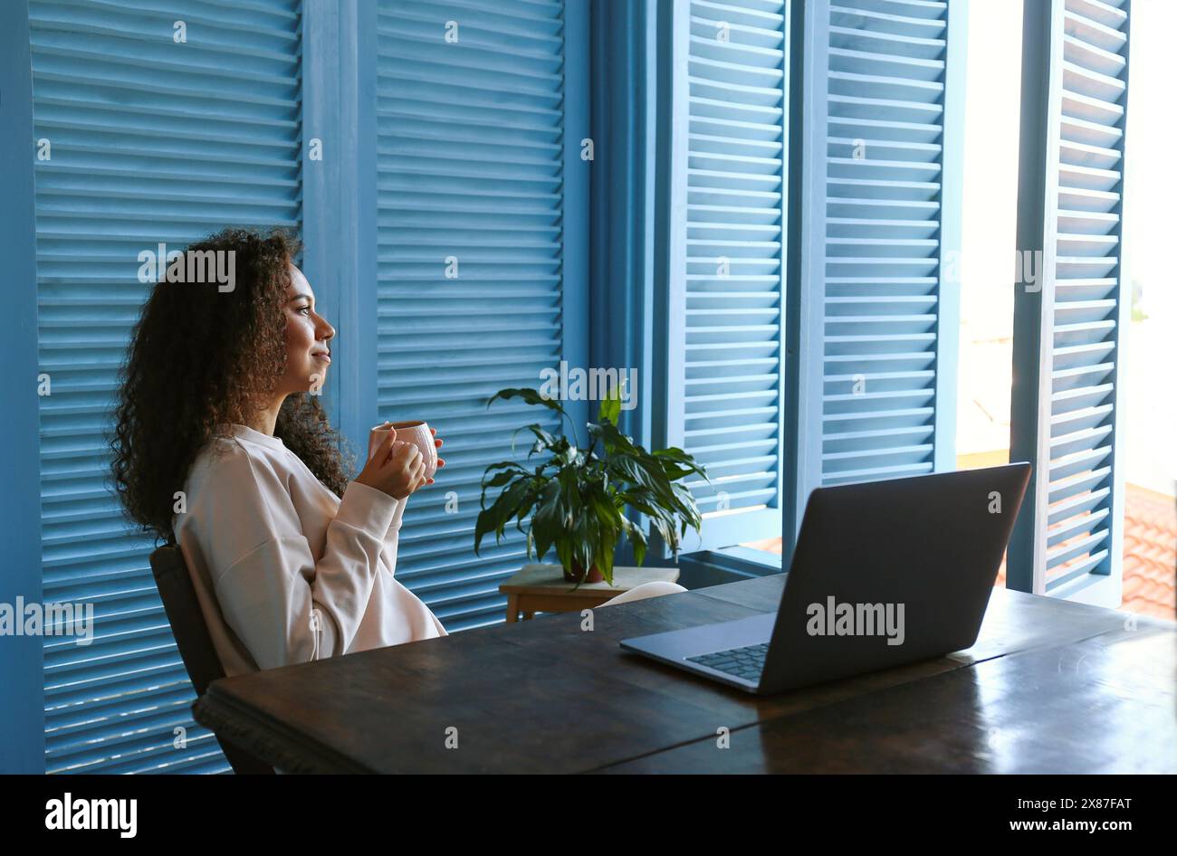 Freelancer taking coffee break from work on laptop at home Stock Photo