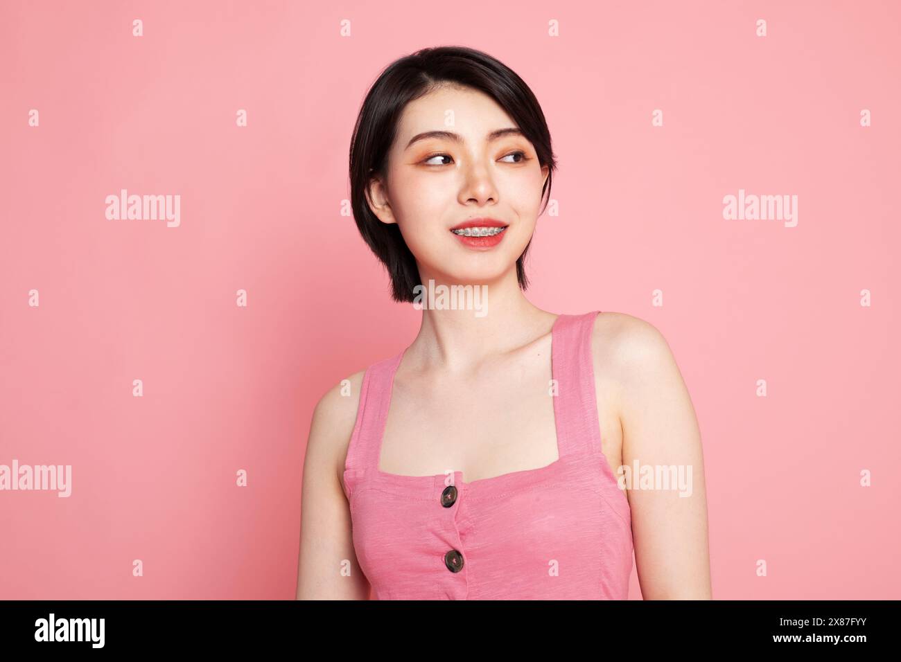 Smiling young woman against pink background Stock Photo