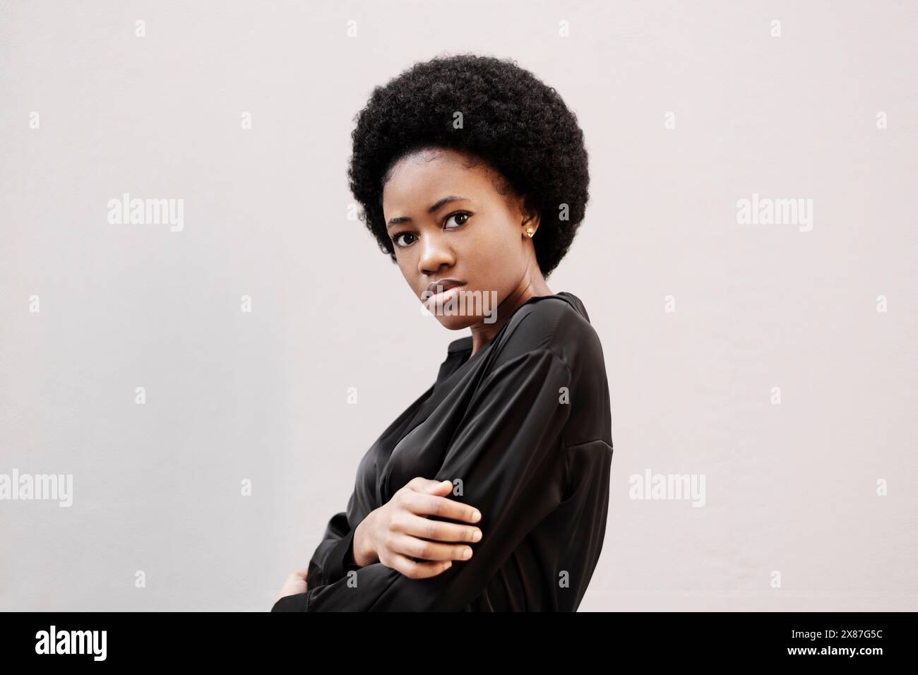 Afro woman wearing black shirt in front of white wall Stock Photo