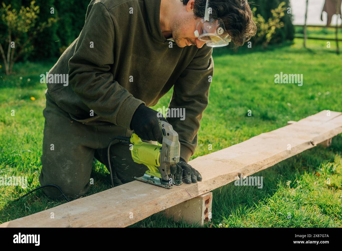 Man cutting plank with electric saw in backyard Stock Photo - Alamy