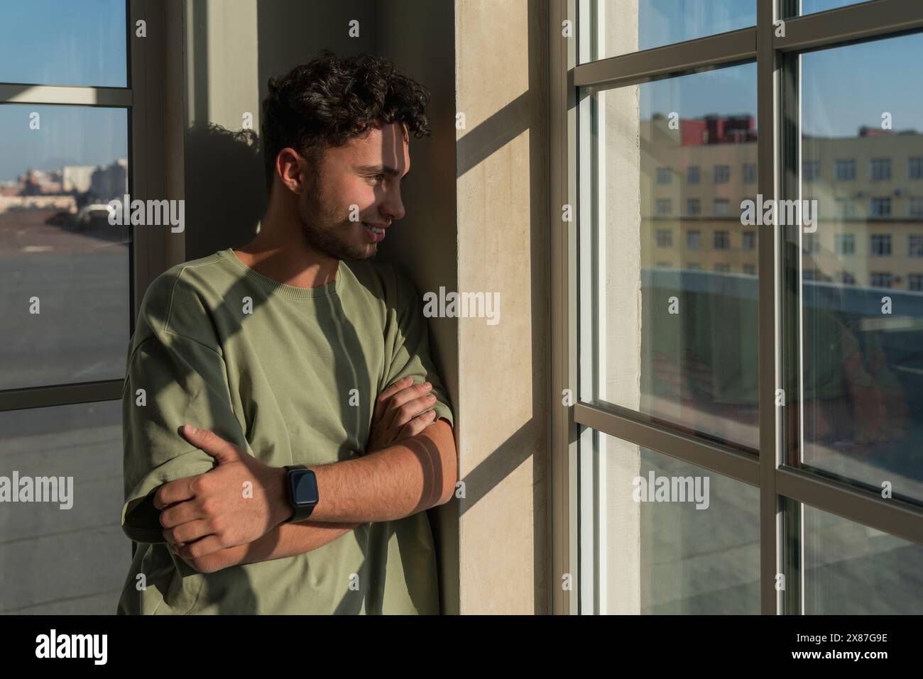 Smiling young man looking through window Stock Photo