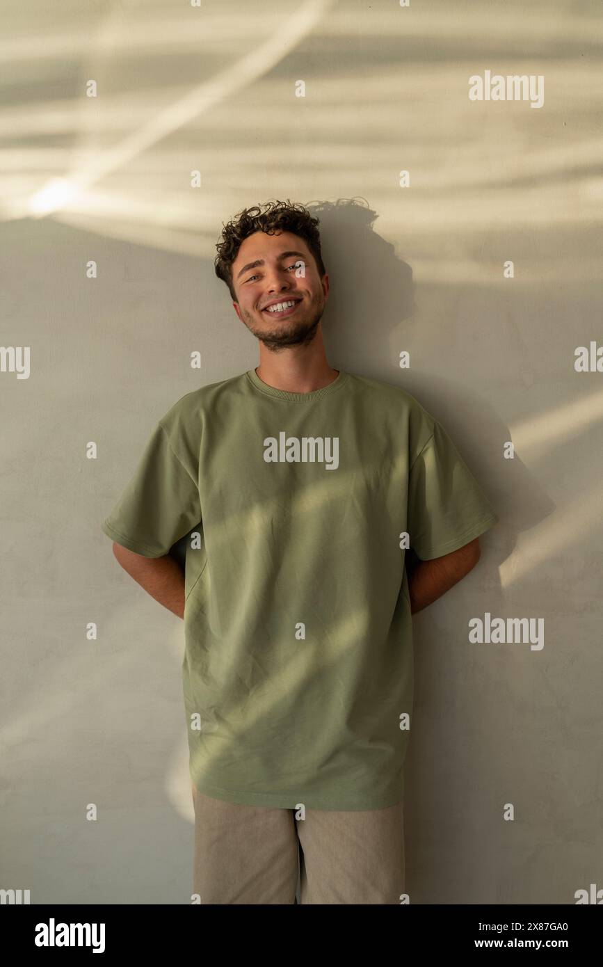 Happy young man leaning on wall Stock Photo