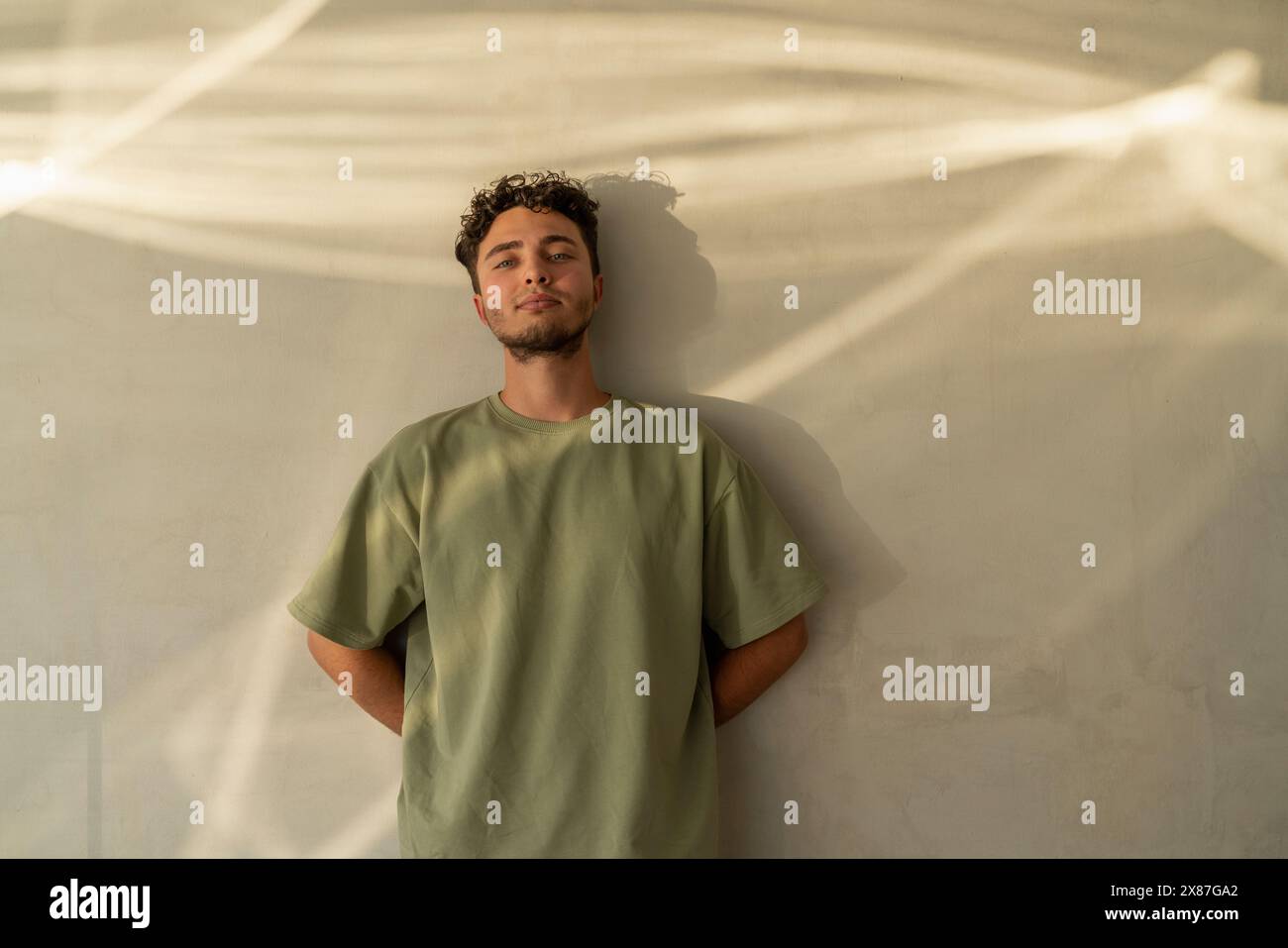 Smiling young man leaning on wall Stock Photo