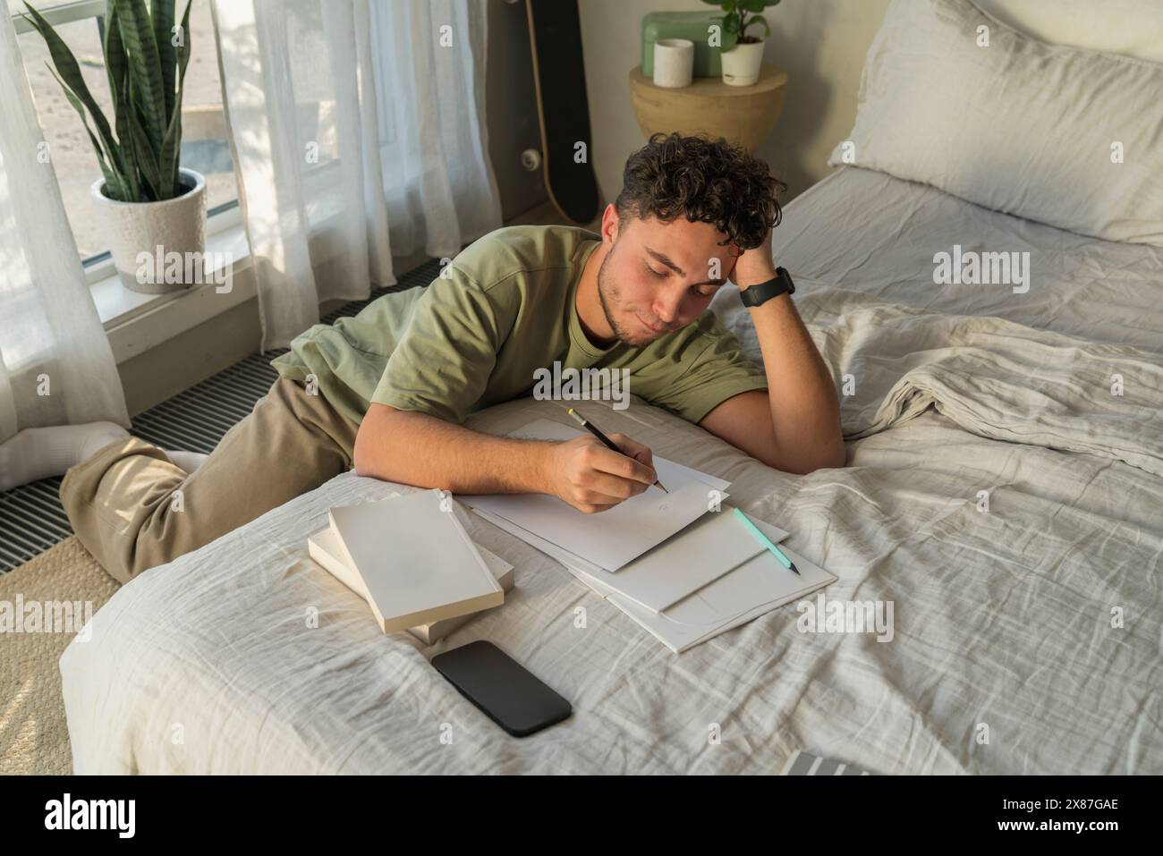 Man leaning and studying on bed at home Stock Photo
