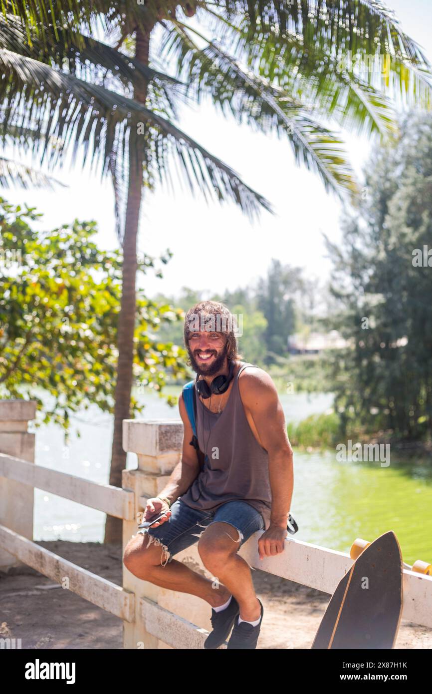 Happy bearded man sitting on railing Stock Photo