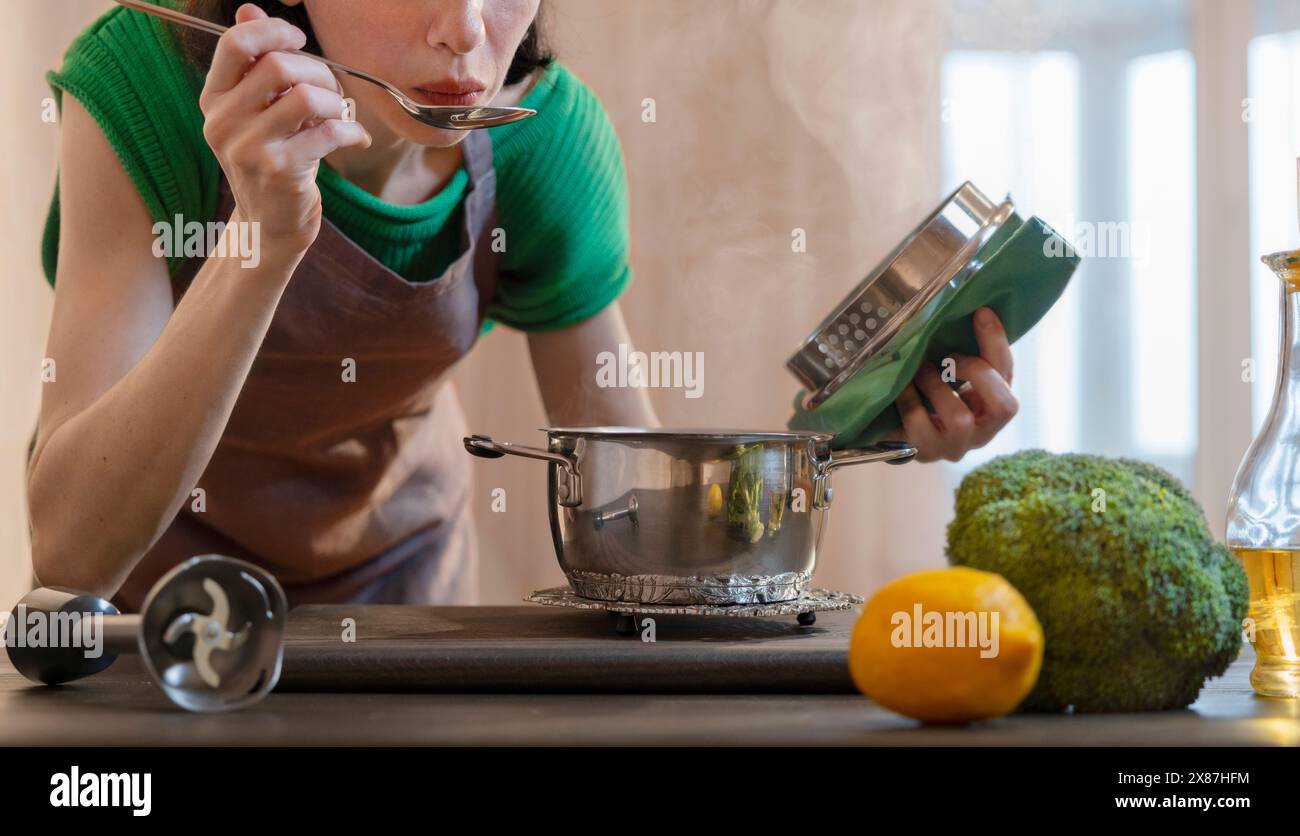 Woman tasting food in kitchen at home Stock Photo