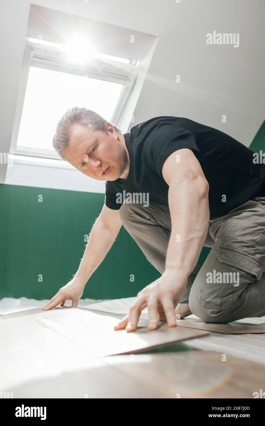 Man adjusting laminated flooring in room at home Stock Photo