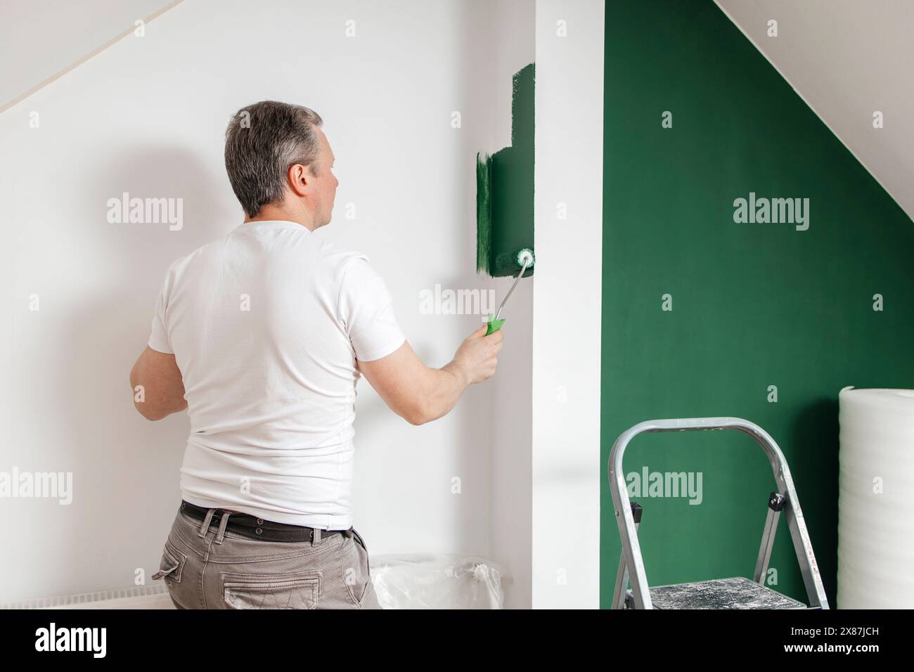 Man painting wall using roller at home Stock Photo