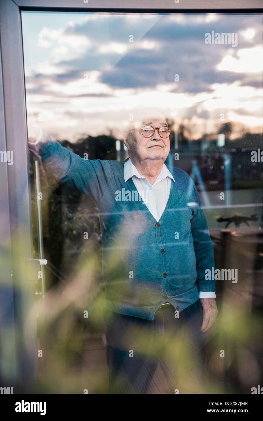Thoughtful senior man looking out through window Stock Photo