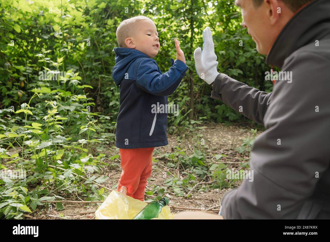 Son and father giving high-five at park Stock Photo