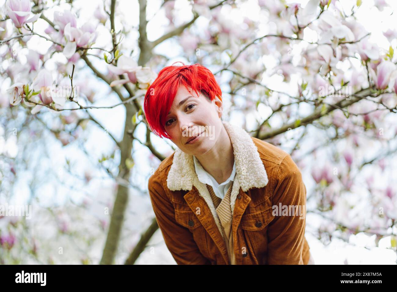 Beautiful redhead woman in front of magnolia tree at park Stock Photo ...