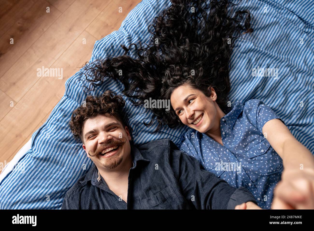 Happy couple lying down on bed at home Stock Photo