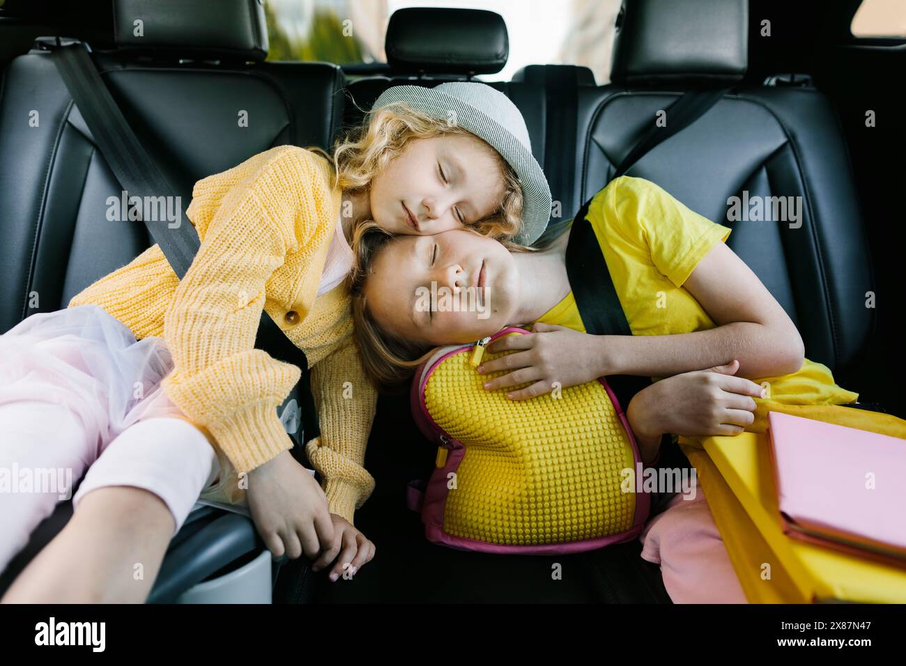 Siblings leaning and sleeping on each other sitting in car Stock Photo