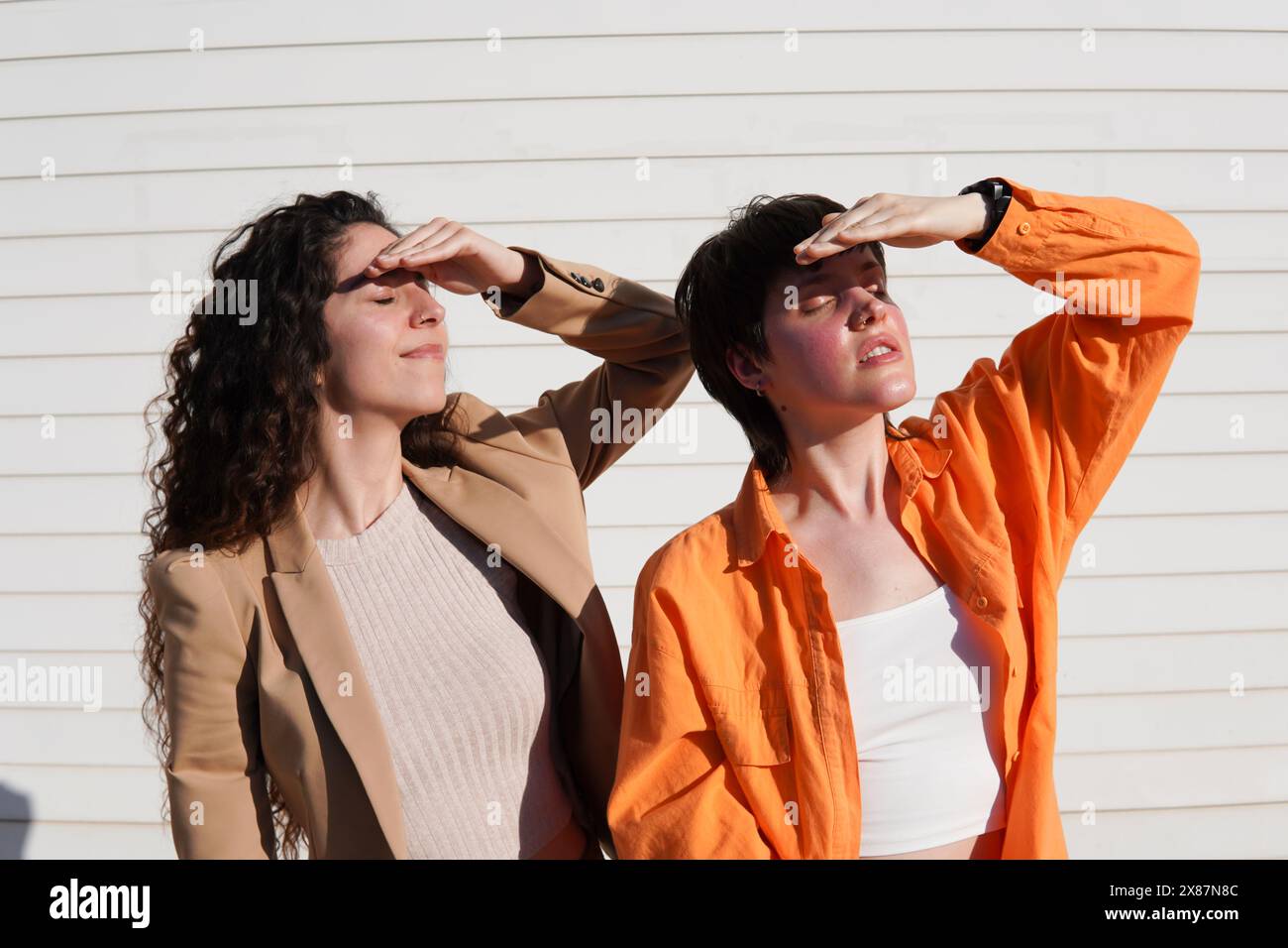 Friends shielding eyes with hands on sunny day Stock Photo