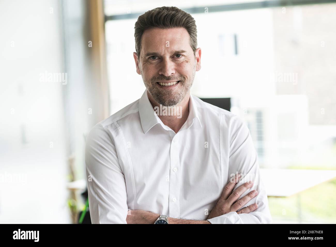 Smiling mature businessman with arms crossed at office Stock Photo