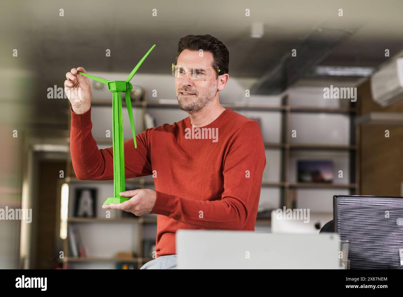 Engineer analyzing green wind turbine model at office Stock Photo
