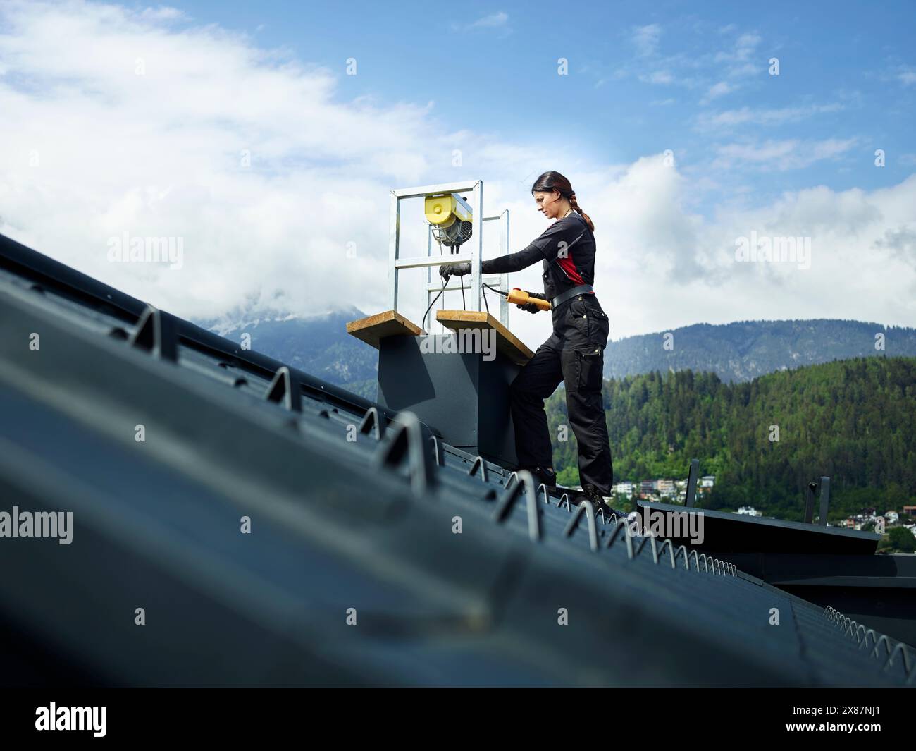Chimney sweeper repairing chimney standing on rooftop Stock Photo