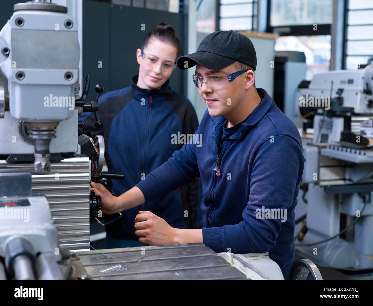 Apprentice operating CNC machine with trainee at factory Stock Photo