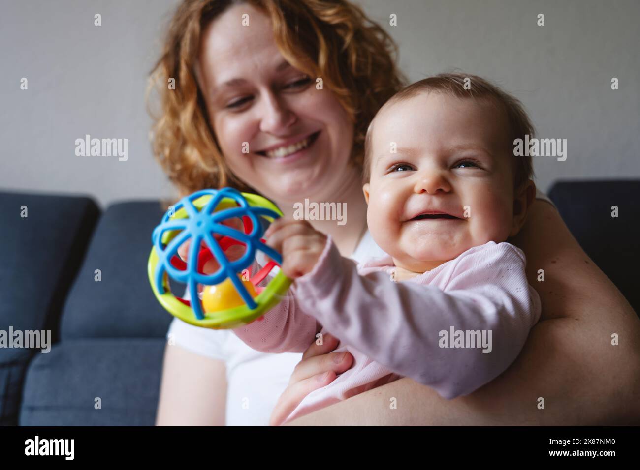 Smiling woman with daughter playing with toy at home Stock Photo