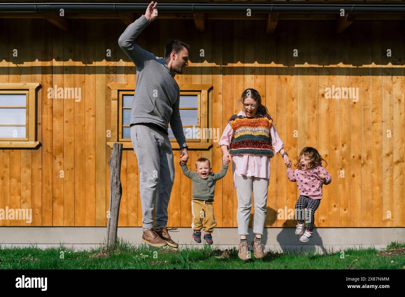 Family jumping together at back yard on sunny day Stock Photo