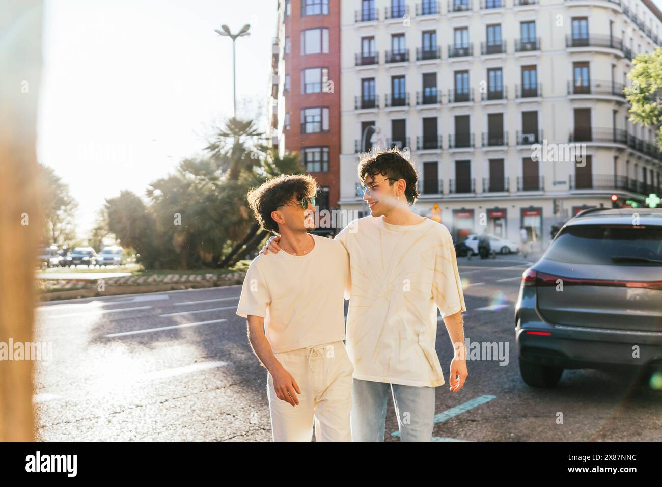 Young gay couple walking with arms around on street Stock Photo