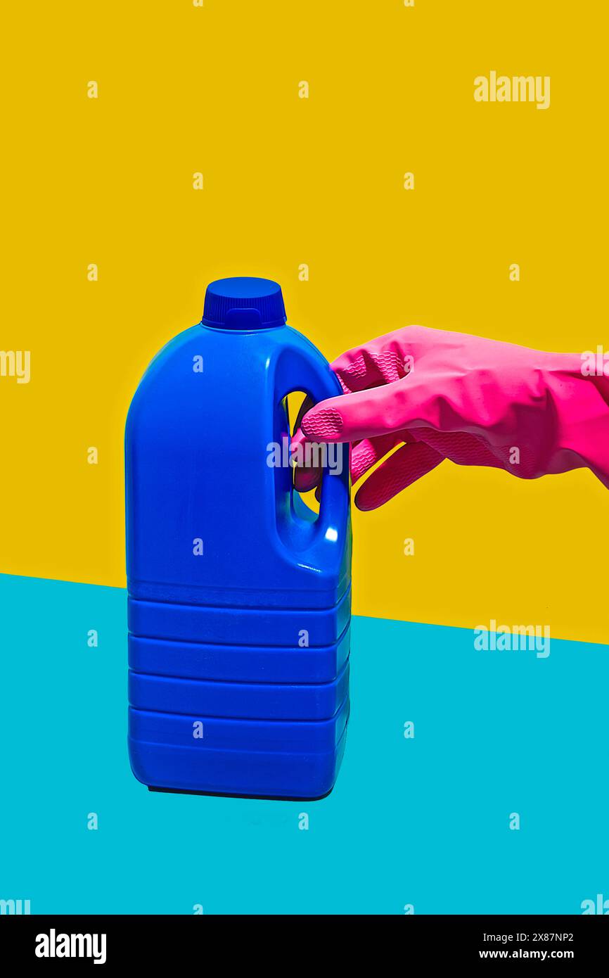 Hand with pink latex glove holding gallon Stock Photo