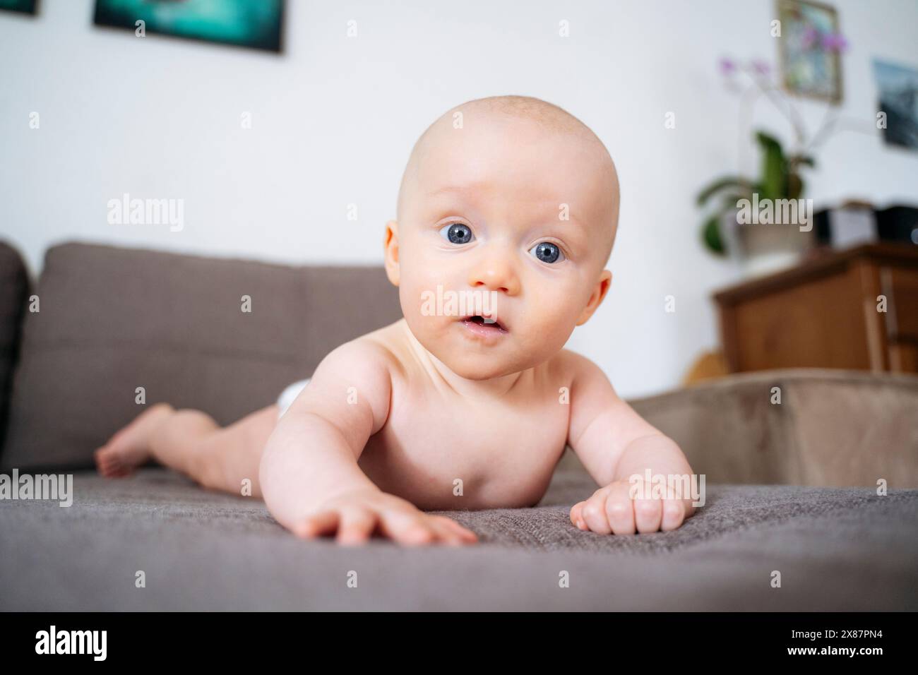 Cute shirtless toddler boy lying on sofa at home Stock Photo