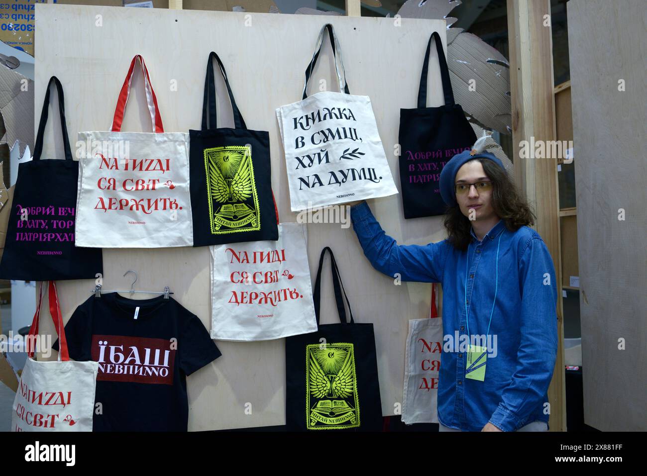Young man seller selling handmade rag bags, letterings in Ukrainian filthy language, stall. Kiev, Ukraine Stock Photo