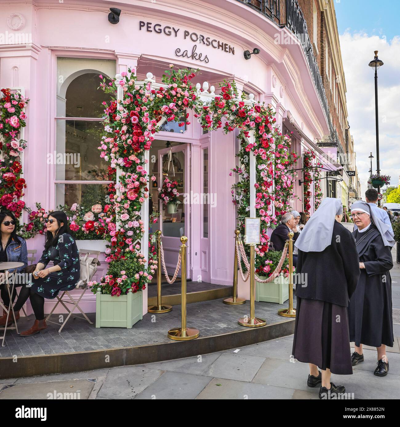 London, UK. 23rd May, 2024. Two nuns admire the display at Peggy Porschen Cakes. The Belgravia in Bloom Festival is returning for its ninth year with a 'Floral Fun and Games' theme. Shops and businesses feature colourful plant and flower displays for this vibrant festival every year. Credit: Imageplotter/Alamy Live News Stock Photo
