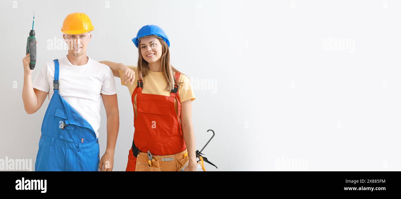 Happy young couple with construction tools on light background with space for text Stock Photo