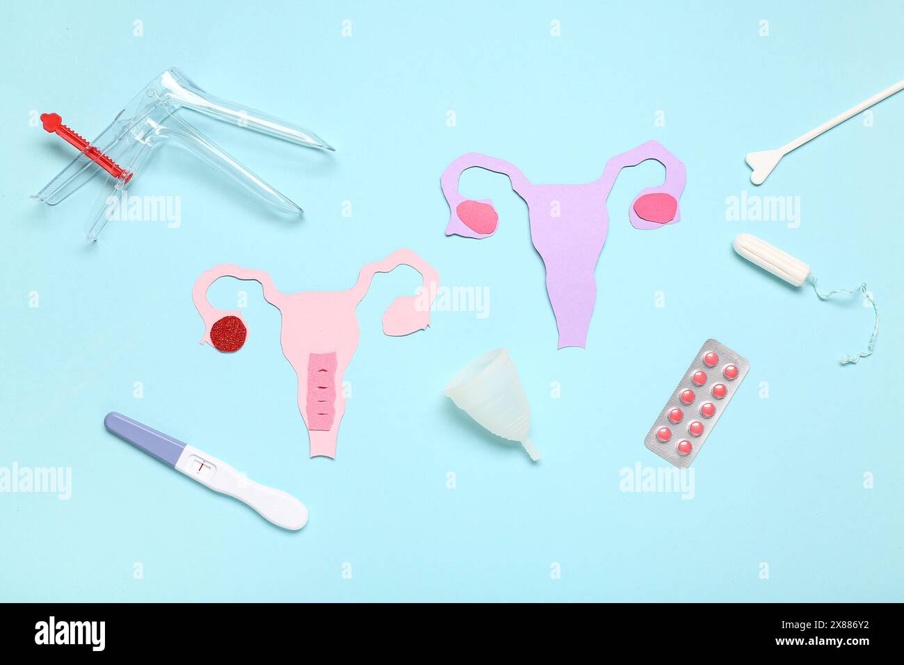 Paper uteruses with gynecological speculum, pills and pregnancy test on