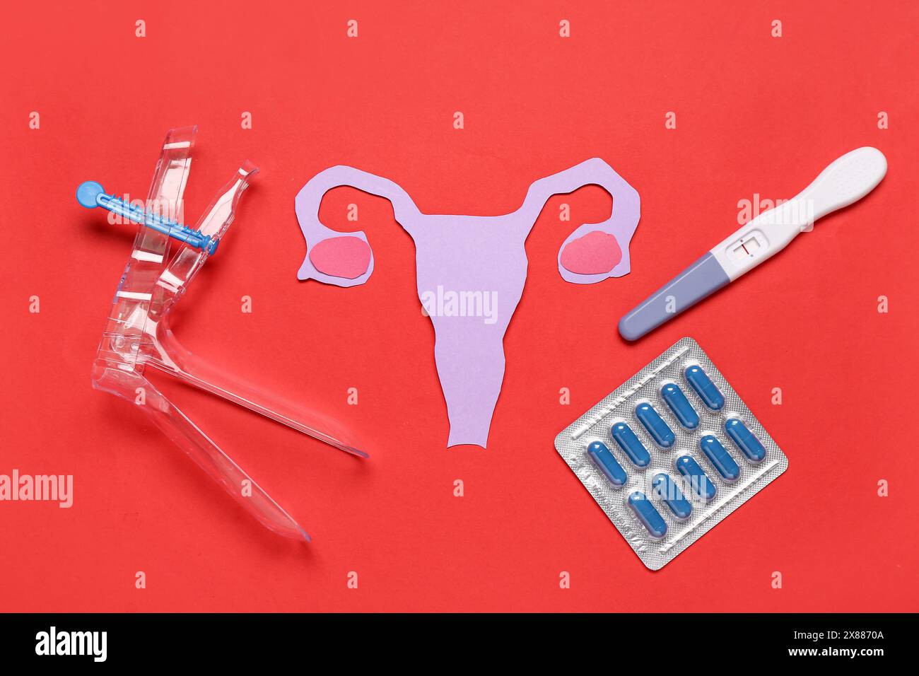 Paper uterus with pills, pregnancy test and gynecological speculum on
