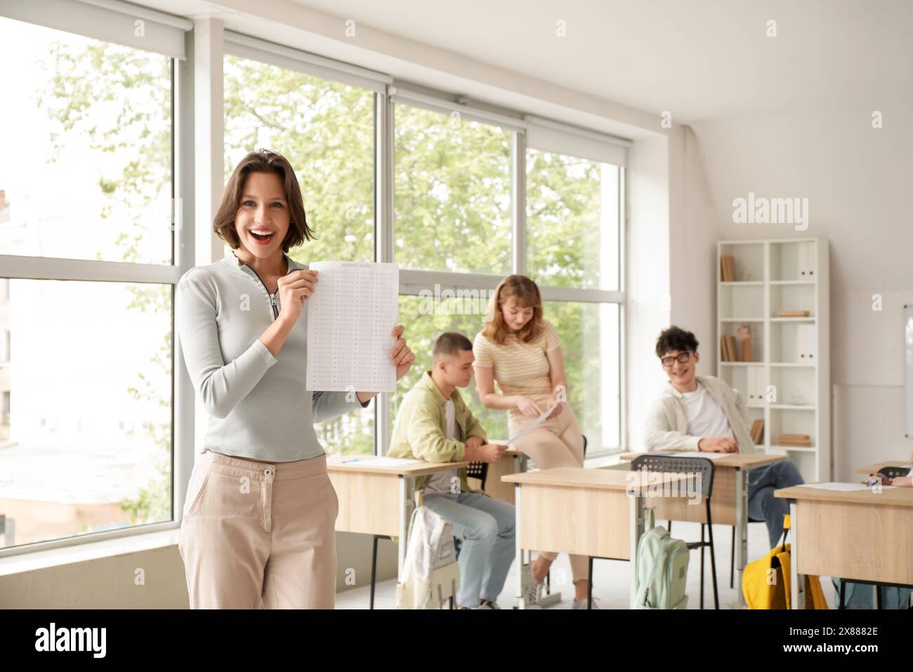 Happy female student with answer sheet after exam in classroom Stock ...