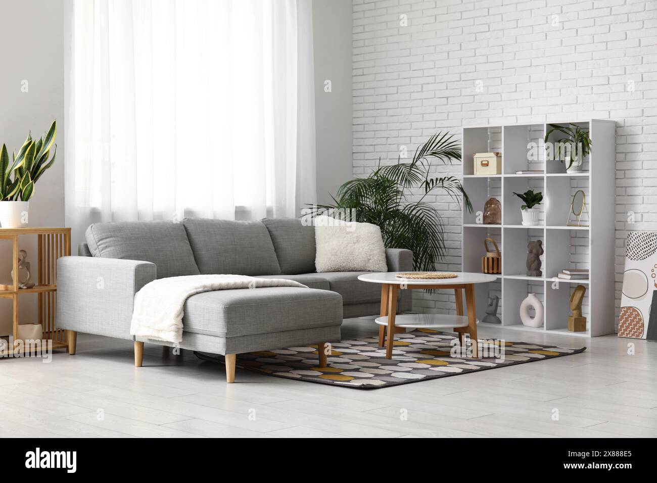 Interior of modern living room with grey sofa, shelving unit and coffee ...