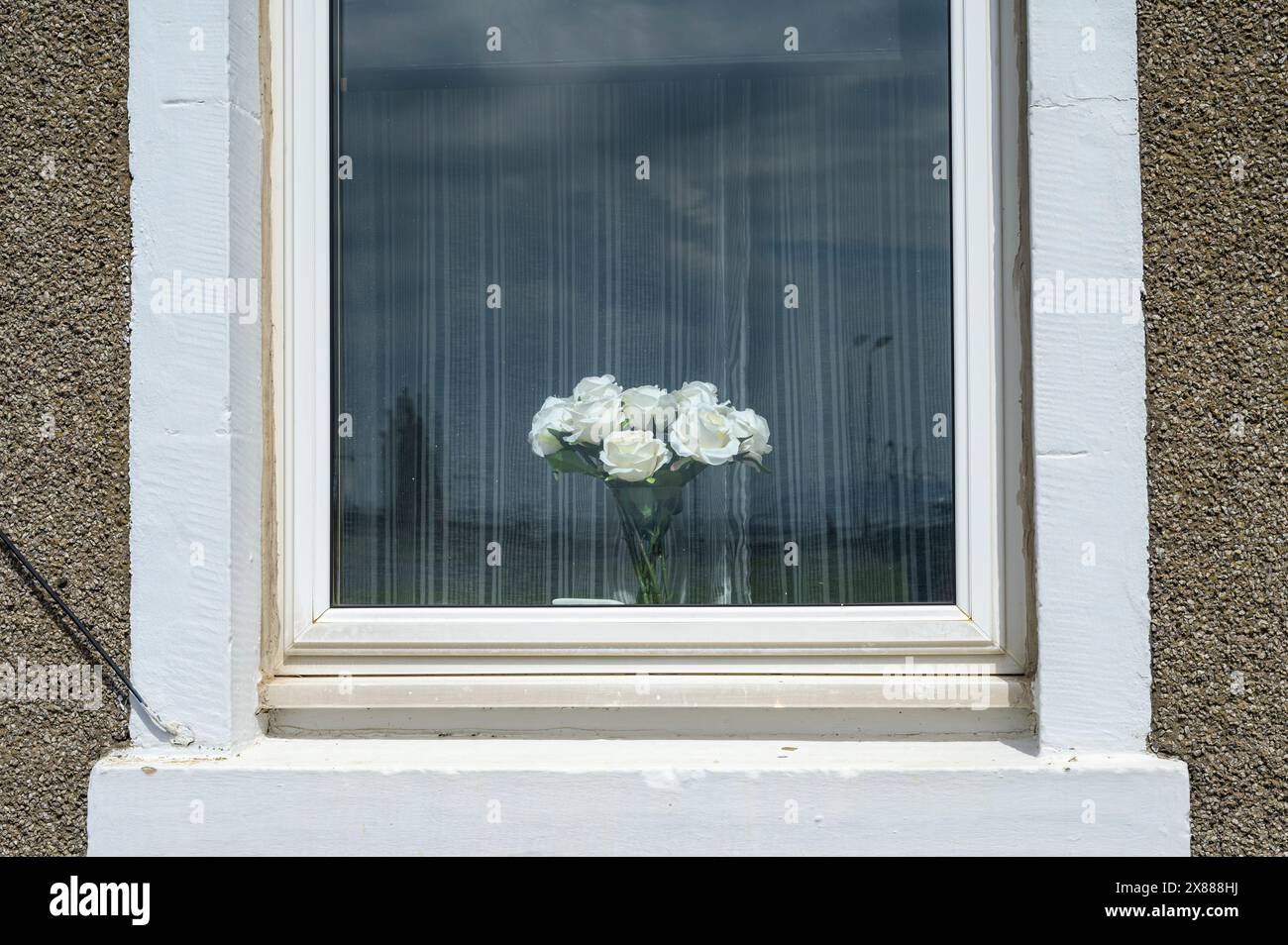 Artificial flowers in a the window of a house Stock Photo