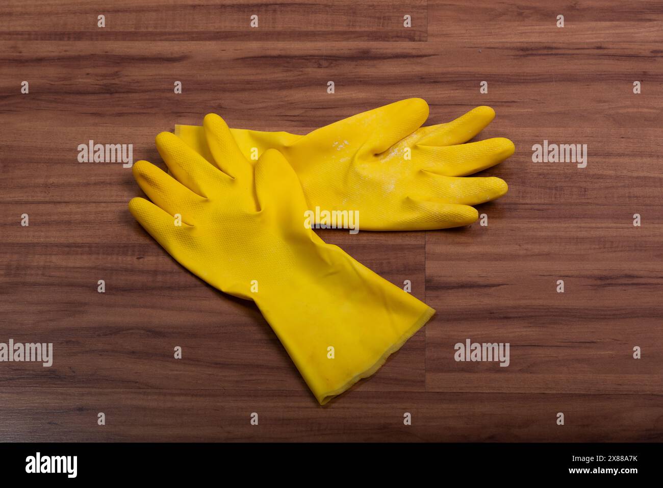 Pair of yellow rubber washing cleaning gloves isolated on wooden background. Stock Photo