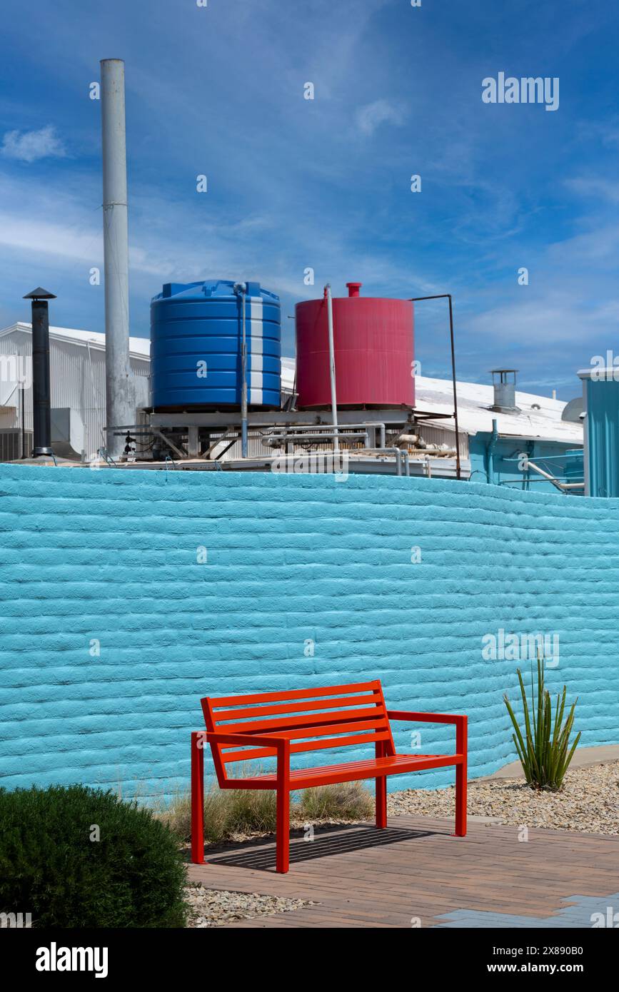 A colorful juxtaposition of MCM design of Spa courtyard, with view over the wall of the red and blue tanks in an industrial setting in Las Cruces, NM Stock Photo
