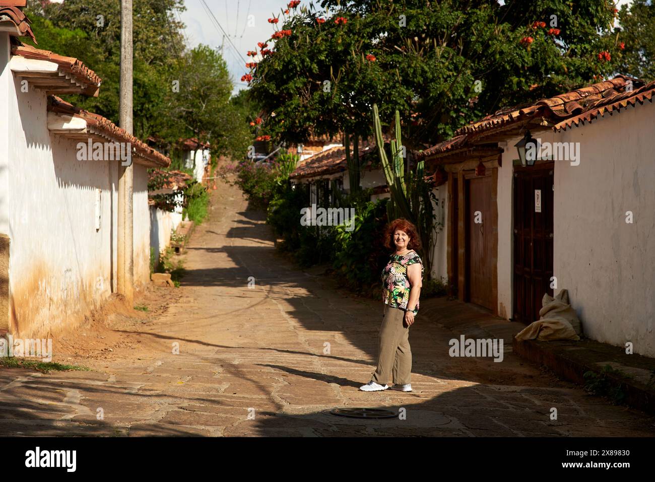Hispanic woman smiling, strolling through the colonial streets of the most beautiful town in Colombia, Barichara. Stock Photo