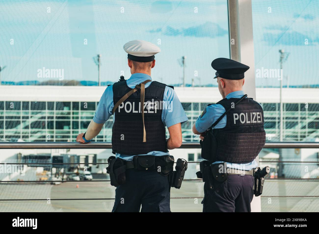 Two armed airport police officers watching over a taxiway at Munich Airport, Germany, from the Terminal 2 outdoor observation deck Stock Photo