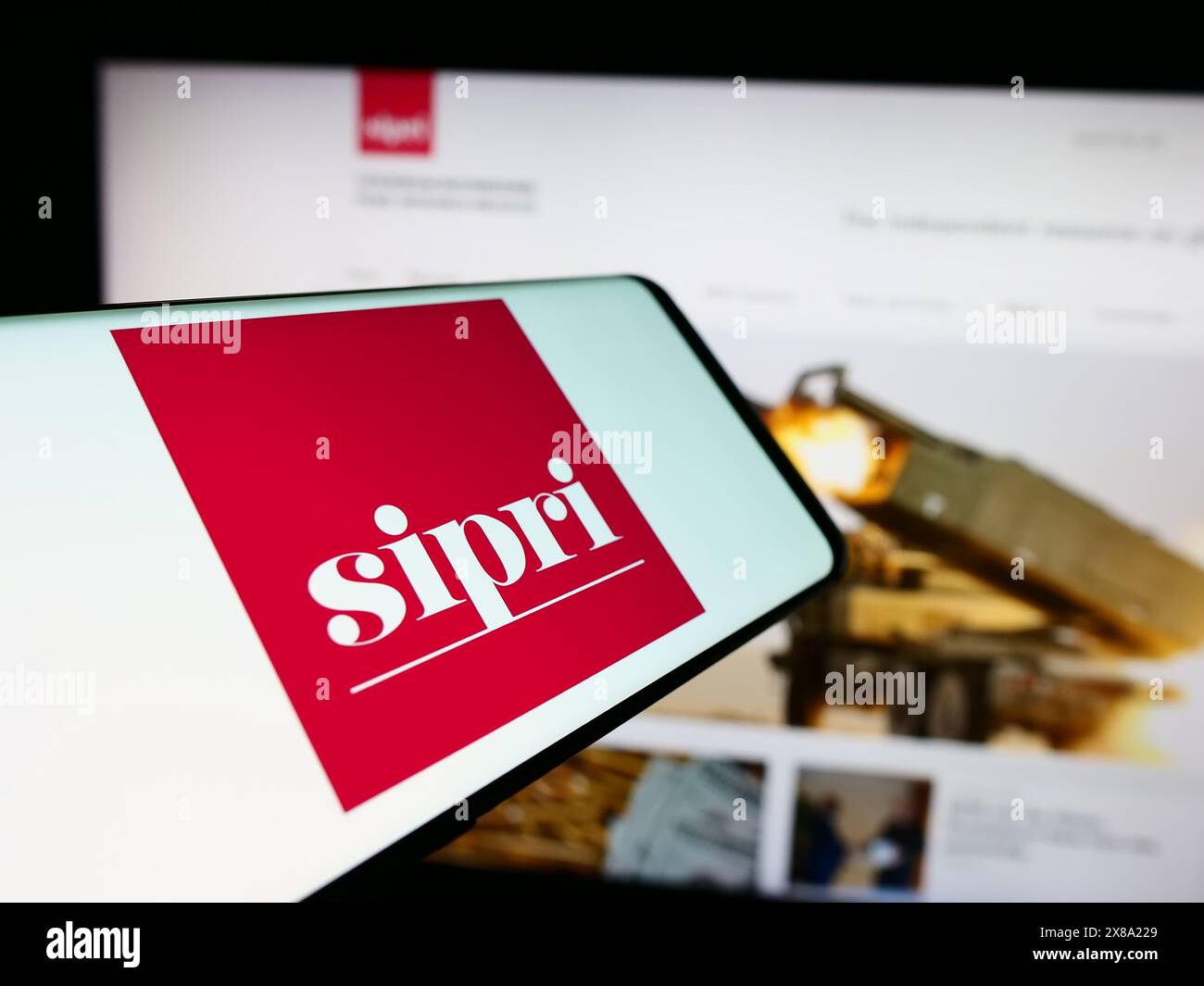 Mobile phone with logo of Stockholm International Peace Research Institute (SIPRI) in front of website. Focus on center-right of phone display. Stock Photo
