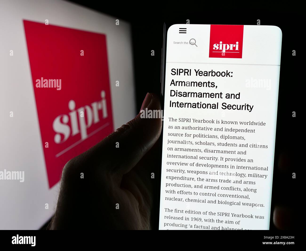 Person holding cellphone with webpage of Stockholm International Peace Research Institute (SIPRI) with logo. Focus on center of phone display. Stock Photo