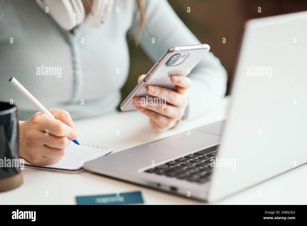 Kyiv, Ukraine. January 21, 2022. Close up of woman using mobile phone and laptop computer on white desk in modern office. Stock Photo