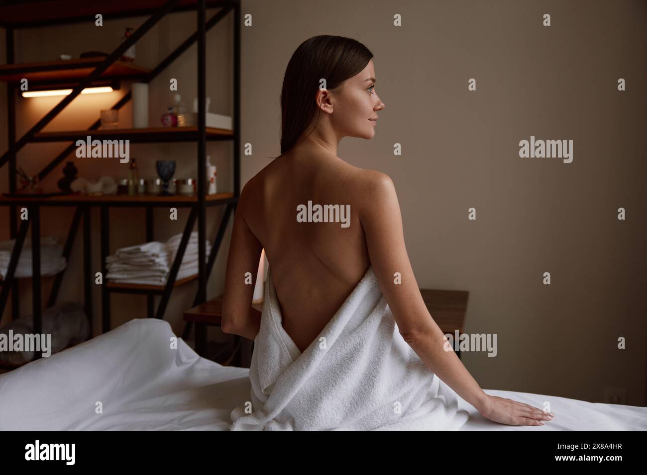 Woman client wrapped in towel sitting on massage table Stock Photo