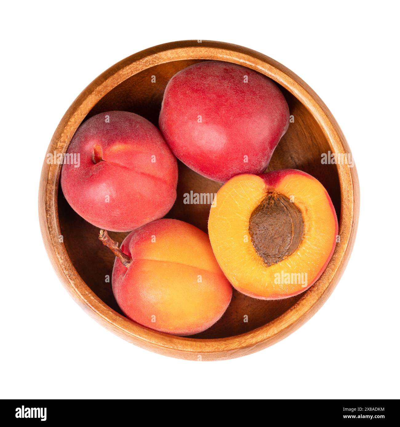 Fresh apricots in a wooden bowl. Stone fruits of Prunus armeniaca, similar to a small peach. Yellow fruits, tinged red on the side most exposed to sun. Stock Photo