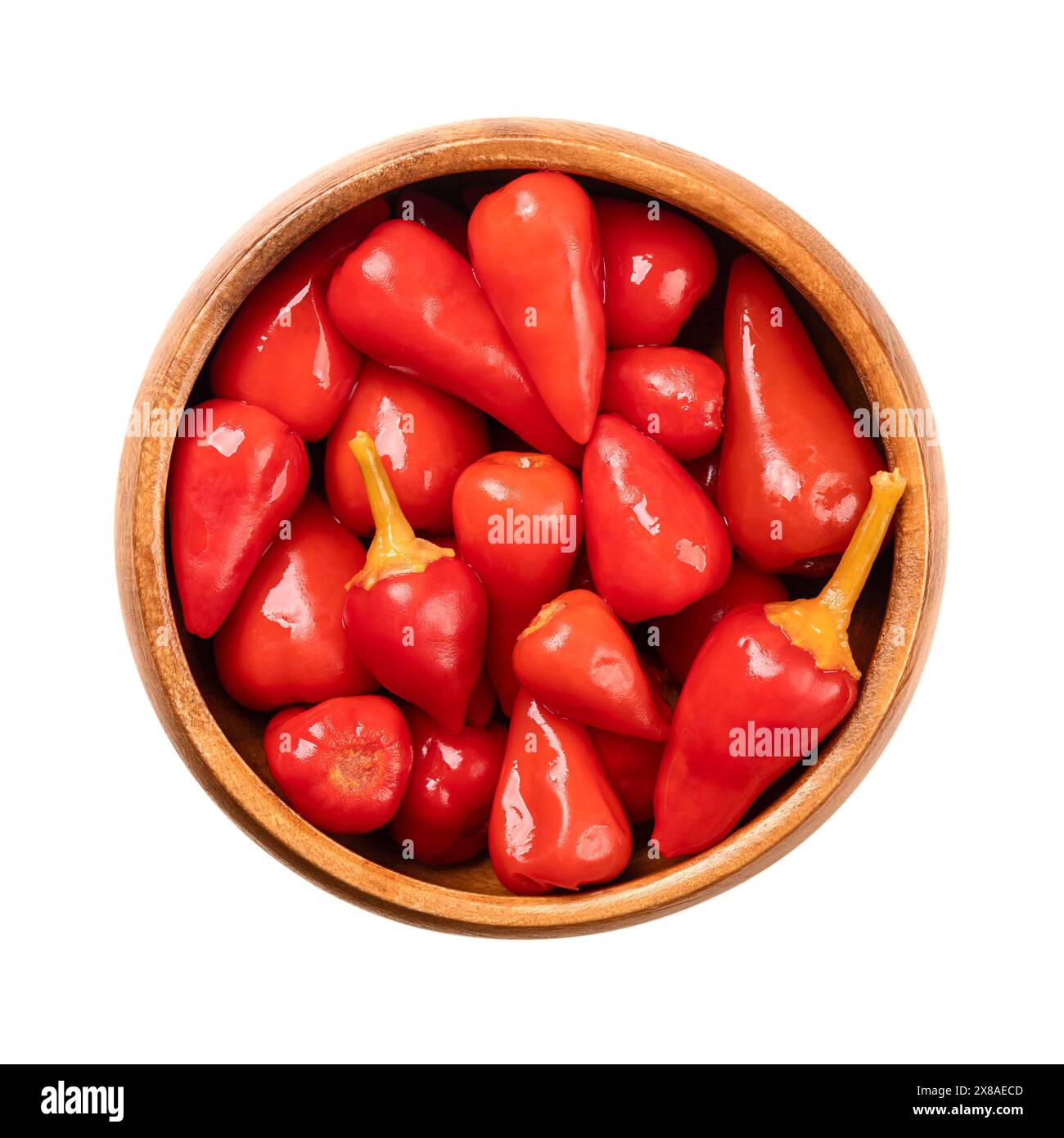Pickled red hot baby peppers, in a wooden bowl. Small hot chilis, pepperonis, or Capsicum pepper, pasteurized and preserved in a vinegar brine. Stock Photo