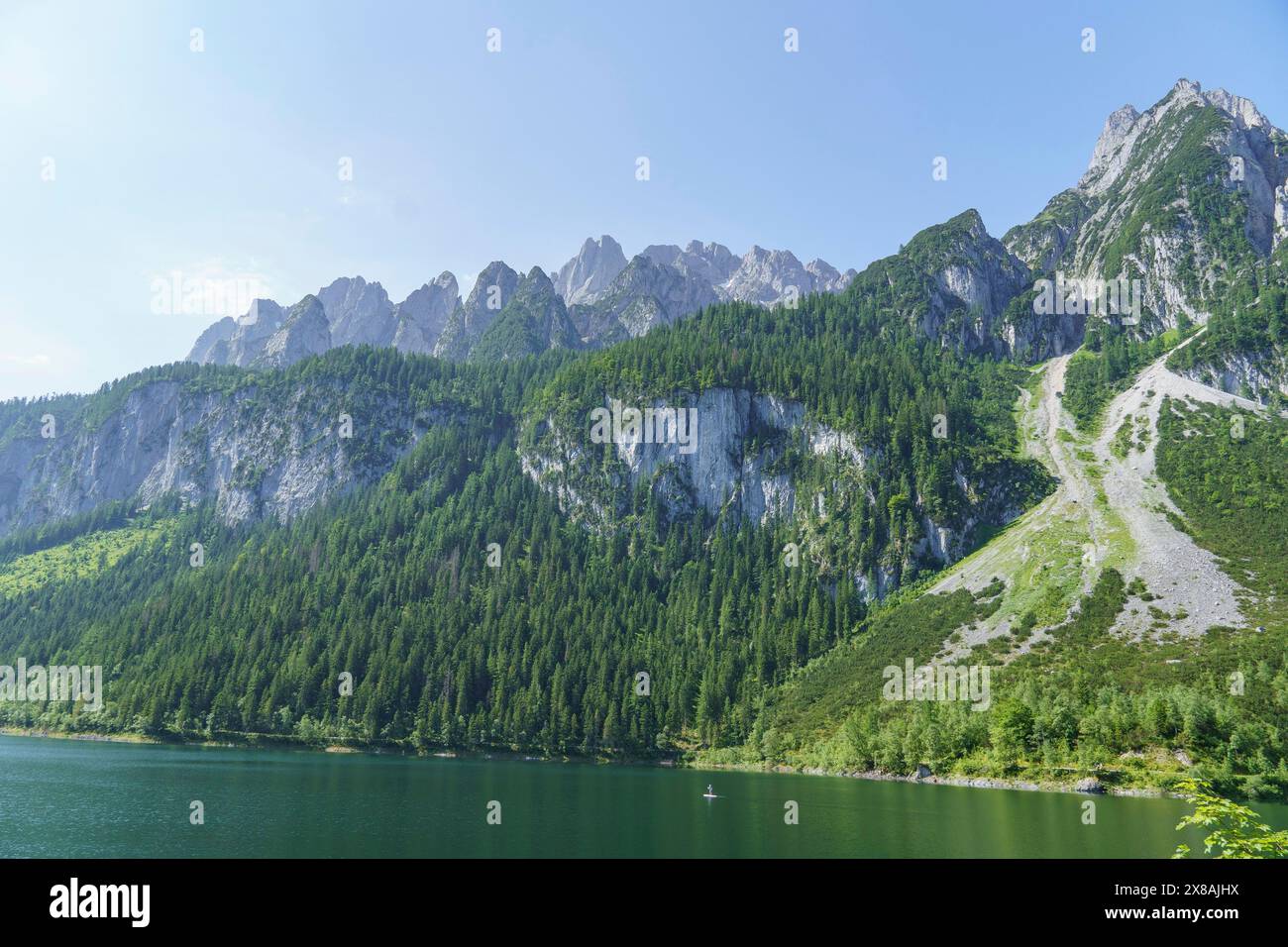 A large lake surrounded by imposing mountains and lush forests under a ...