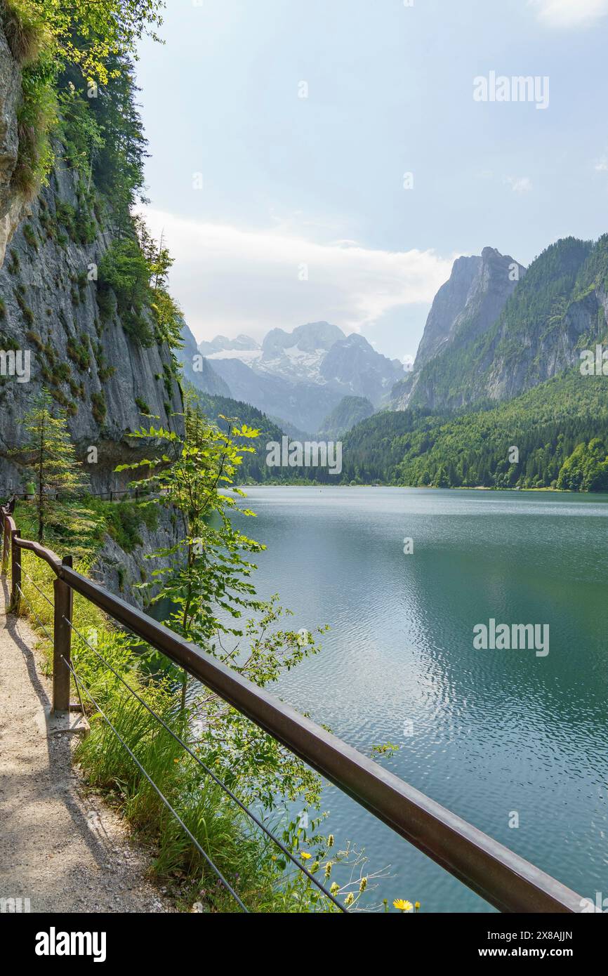 Hiking trail with railing along a lake, surrounded by forested ...