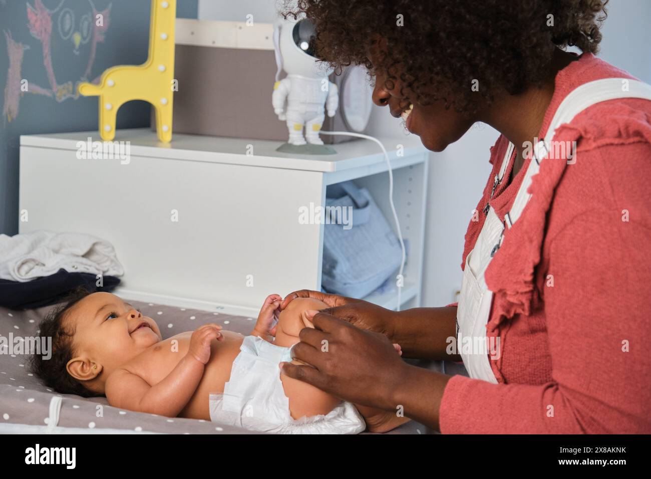African woman is diapering a baby on a changing table Stock Photo Alamy